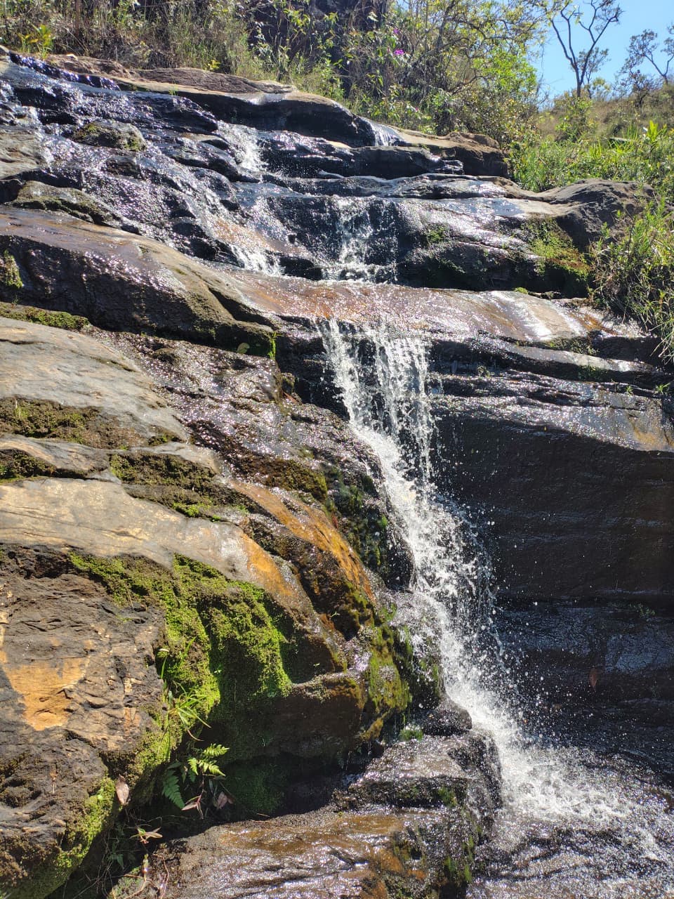 Cachoeira descendo por rochas cobertas de musgo