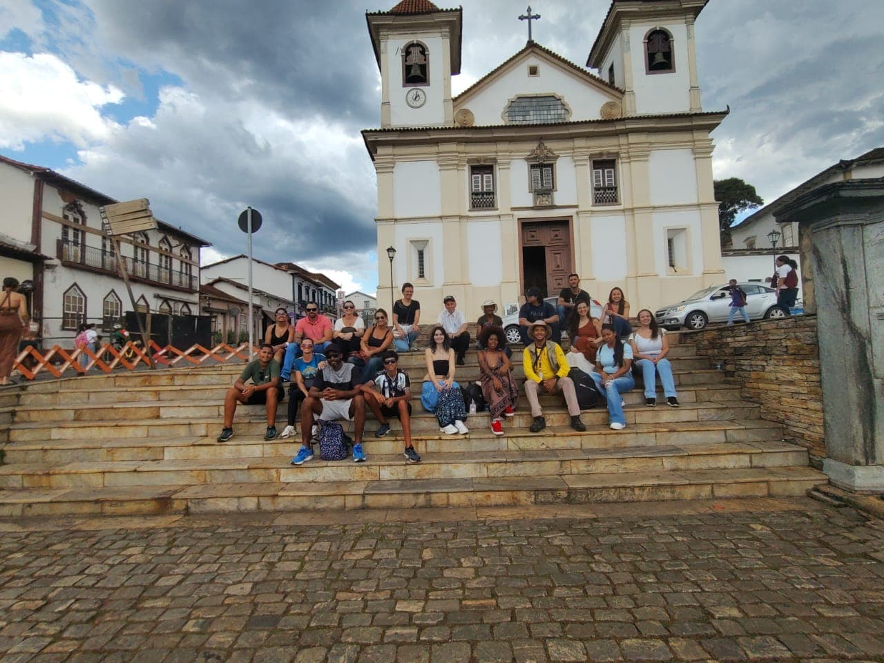 Grupo de visitantes na escadaria de uma igreja colonial