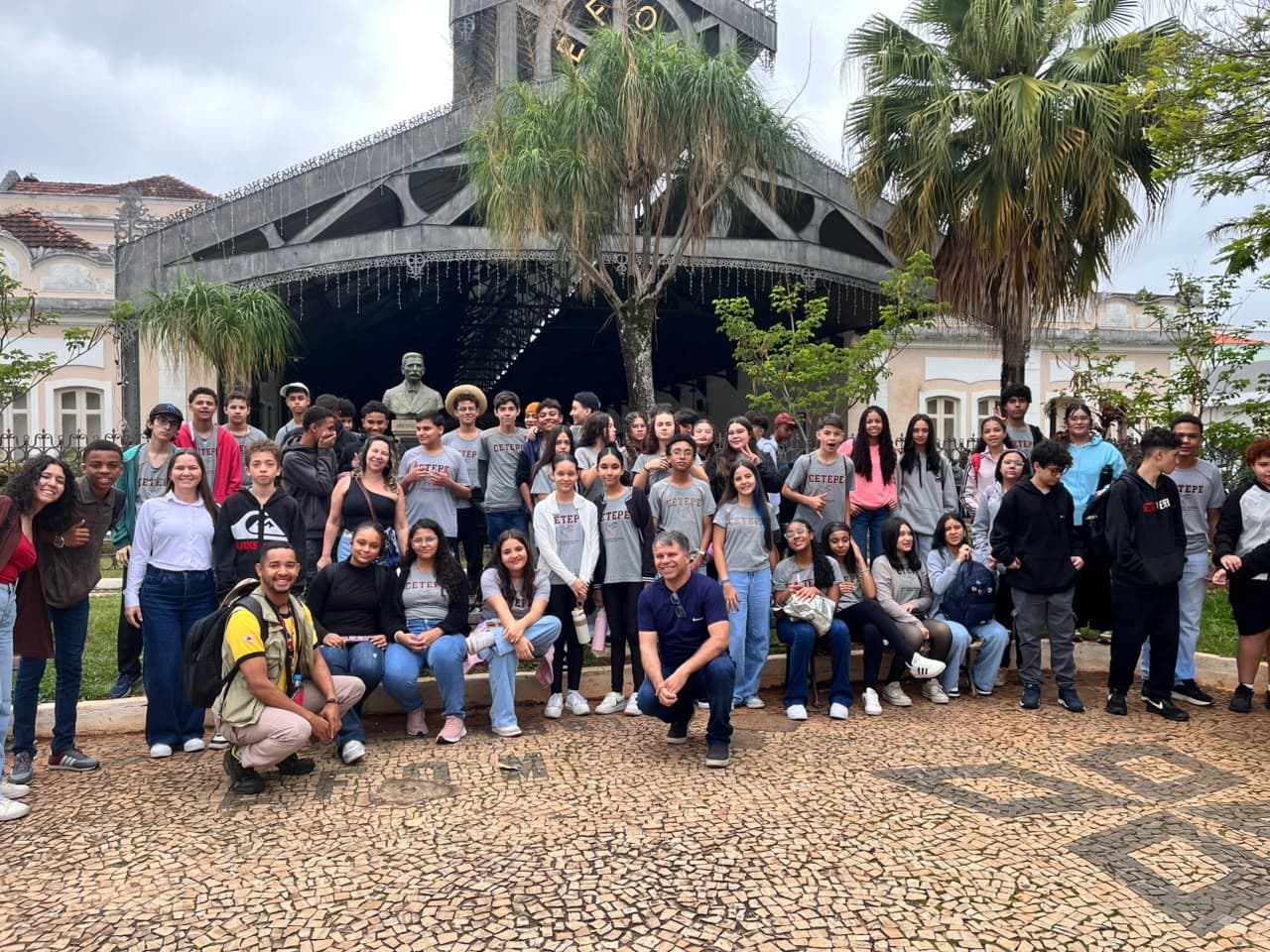 Grupo de estudantes reunido diante de uma estação histórica com palmeiras
